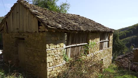 cabaña con paredes de piedra y techo gris en el paisaje rural en el pueblo de montaña en los balcanes