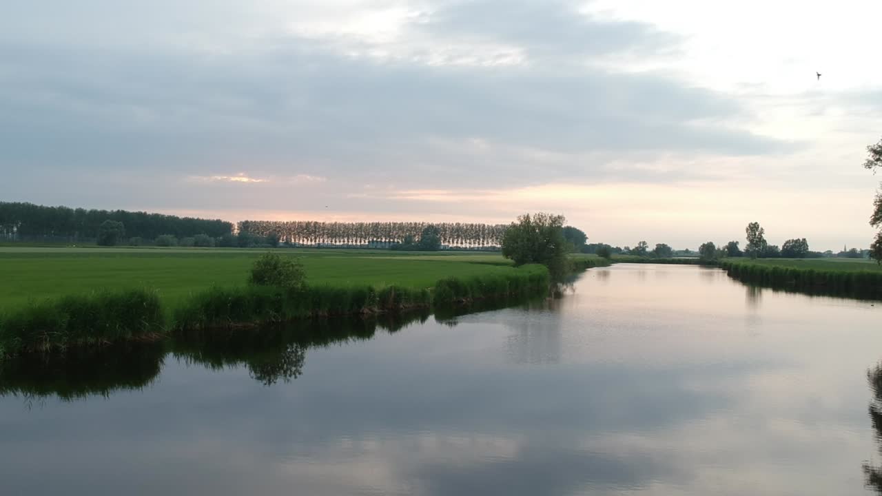 낮은 각도 무인 항공기 보기에서 녹색 필드로 둘러싸인 하늘 반사와 강