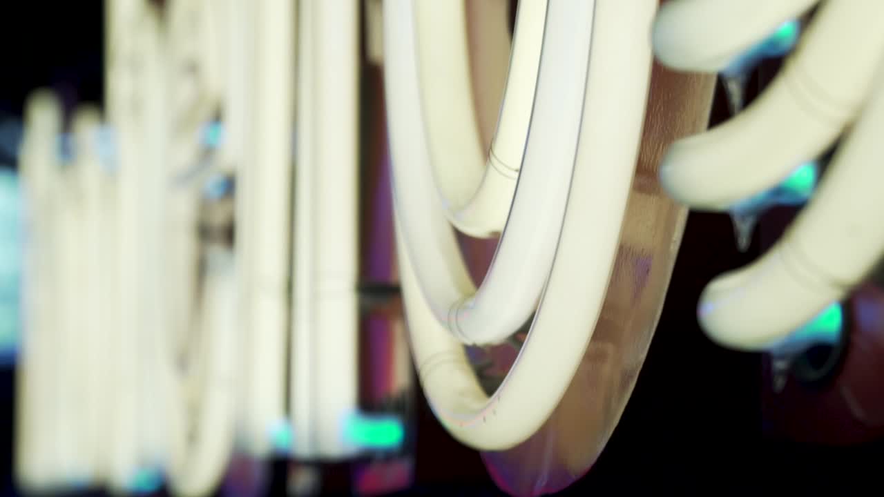 뒤에 흐릿한 네온이 있는 흰색 네온 사인의 슬로우 모션 샷을 닫습니다.