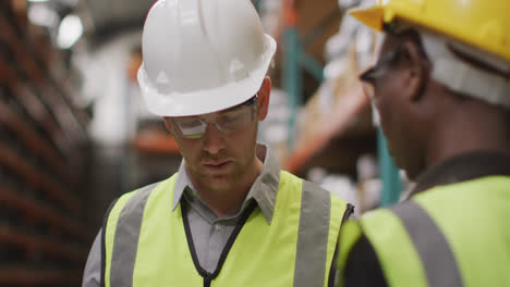 Caucasian-male-factory-worker-at-a-factory-wearing-vis-vests,-hard-hats-and-glasses