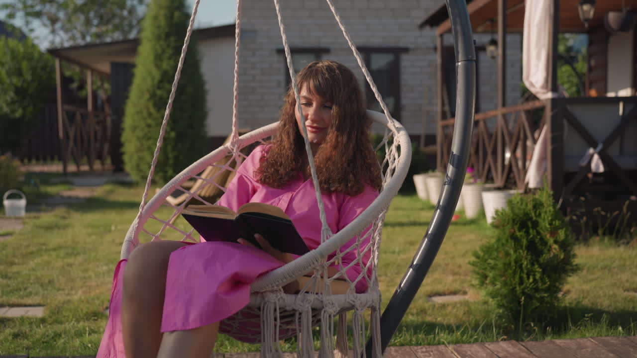 Woman Enjoying Outdoors On Swing Chair, Joyful Woman Sitting On Hanging Chair In Sunny Backyard, Happy Woman Relaxing On Swing Seat Amidst Bright Outdoor Surroundings With Lively Energy