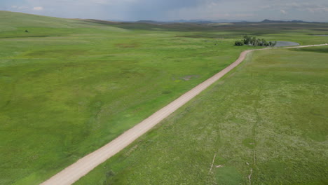 aerial view of dirt road in the middle of vast green valley