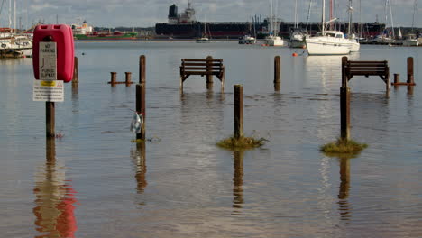 wide shot of benches and pathway flooded at high tide at ashlett creek in the solent, southampton