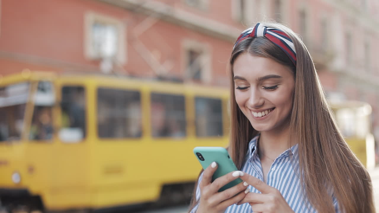 Giovane donna felice che usa lo smartphone in una strada cittadina