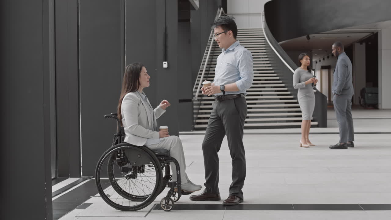 Businesswoman with Disability Having Talk with Male Asian Colleague