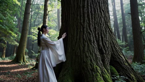 Woman in Traditional Attire Interacting with an Ancient Tree in a Serene Forest