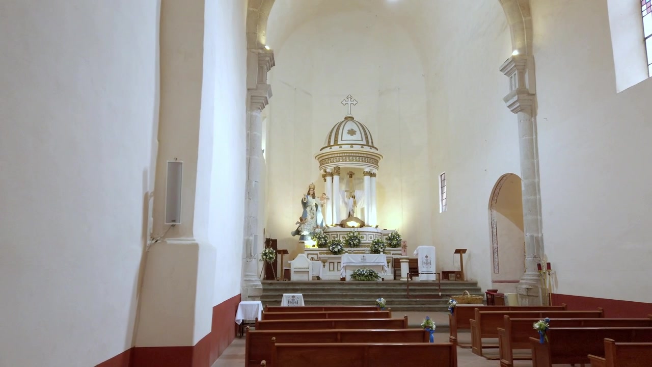 Interior de iglesia histórica con altar religioso, bancos de madera, arquitectura abovedada y una atmósfera espiritual pacífica durante el día en México.