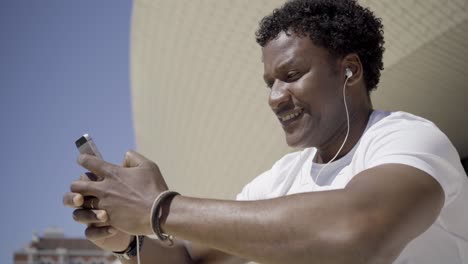 hombre afroamericano sonriente escuchando música con auriculares