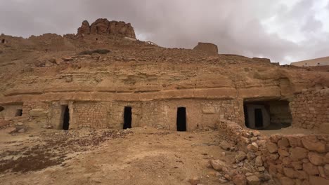 Ksar-Guermessa-troglodyte-village-in-Tunisia-on-cloudy-day,-panning-view