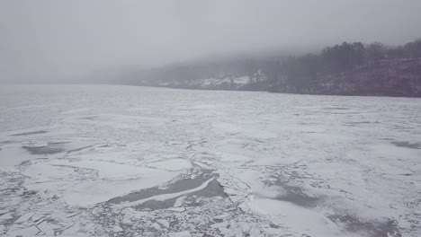 drone flying above a foggy river with big ice chunks during a winter storm in connecticut