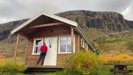 Blonde-caucasian-female-tourist-coming-out-from-a-log-cabin-accommodation-in-a-peaceful-morning