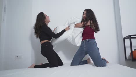 two friends having a pillow fight on a bed