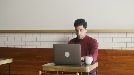 man working on laptop in coffee shop