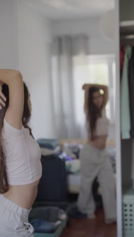 woman dancing in front of a mirror in a messy bedroom