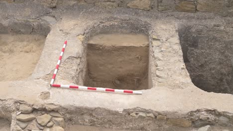 overview of an active archaeological excavation site with visible ancient stone structures and tools