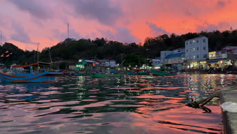 Orangefarbener-Sonnenuntergang-Bei-Nam-Du-Island-Mit-Wasser,-Booten-Und-Gebäudehintergrund