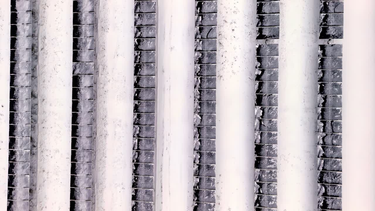 垂直な白い柱とテクスチャーのあるレンガの表面が反復する建築模様を作り出すクローズアップ