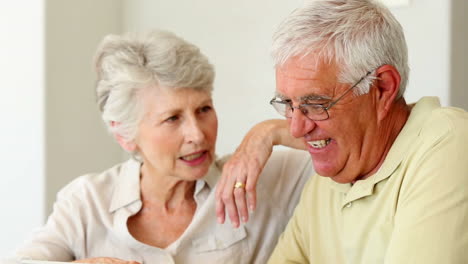 Senior-couple-sitting-at-the-table-using-tablet-pc