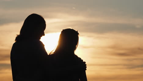 Silhouettes-Of-Mom-And-Daughter-Against-The-Sky-And-Setting-Sun