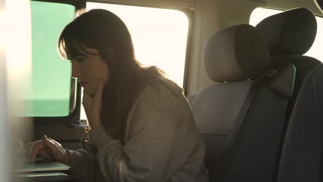 traveling woman working on laptop in van