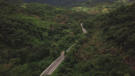 aerial view of countryside road passing through the lush greenery and foliage tropical rain forest mountain landscape