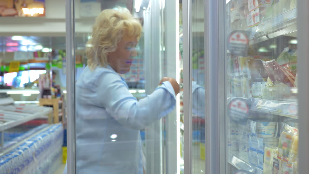 mujer comprando comida en la sección de productos lácteos del refrigerador