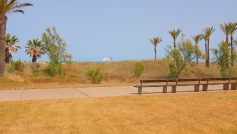 Banco-De-Madera-Vacío-En-El-Paseo-Marítimo-Con-Vistas-Al-Mar-Azul-Durante-El-Verano