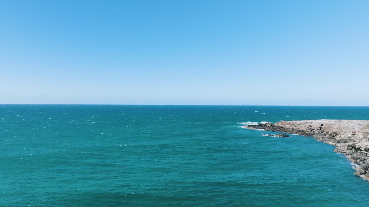 수평선을 향해 짙은 푸른 물 위로 바위가 많은 섬 해안을 따라 비행