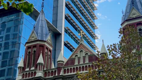 Spires-of-Trinity-Church,-Perth-CBD,-WA-with-blue-sky-and-glass-skyscraper-background