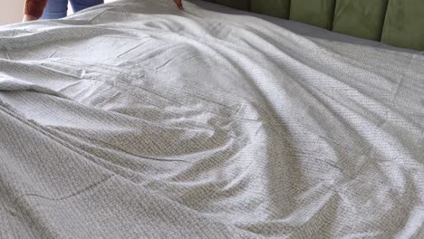 making the bed with grey patterned sheets