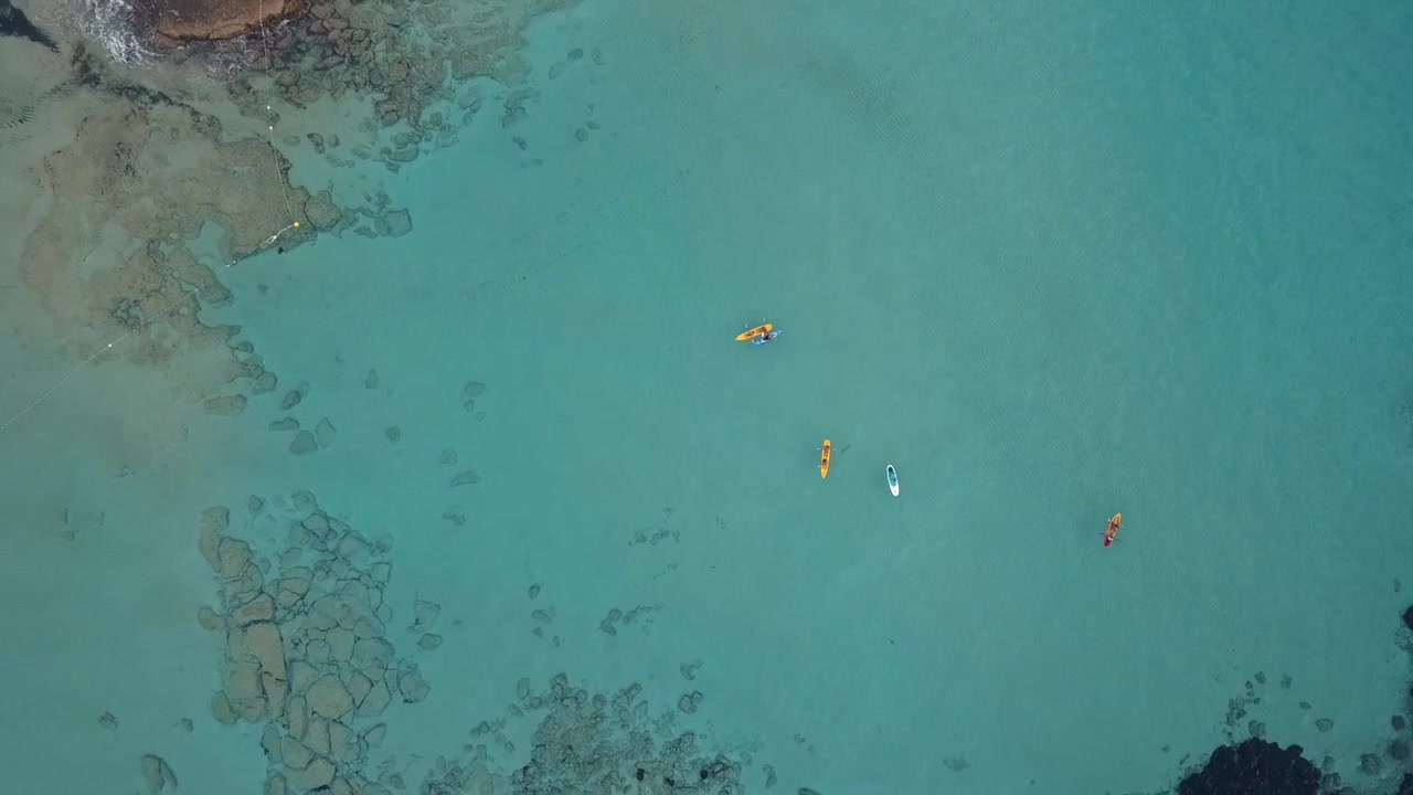 Rocket Drone Shot of a Group of Kayaks on an Expedition Through the Crystal Clear Waters of Cala Comte in Ibiza, you can see the incredible seabed of the coast
