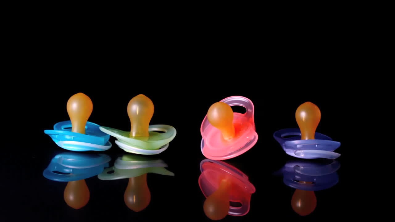 Baby pacifier falling beside three others