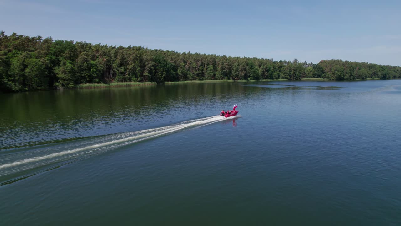 мальчик держит польский национальный флаг перед красной моторной лодкой, эпический после дронового выстрела