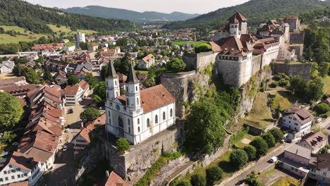 Dramatic aerial close-up of Aarburg Castle and the twin-spired church perched above the Aare River, showcasing the historic heart of Aarburg in Switzerland's canton of Solothurn