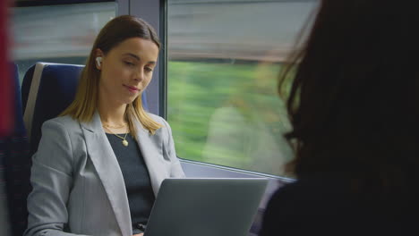 Businesswoman-With-Wireless-Earbuds-Commuting-To-Work-On-Train-Working-On-Laptop