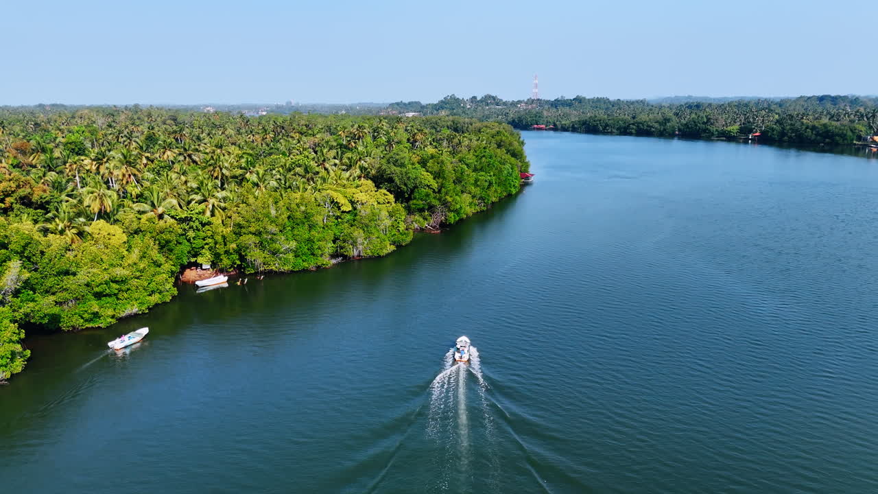 Motor boats moving by the river on clear sunny day. Lush tropical forest grows on the waterfronts. Nature of Sri Lanka. Top view.