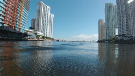 view from a small watercraft as it passes through the calm waters of a narrow channel with tall buildings on either side miami florida