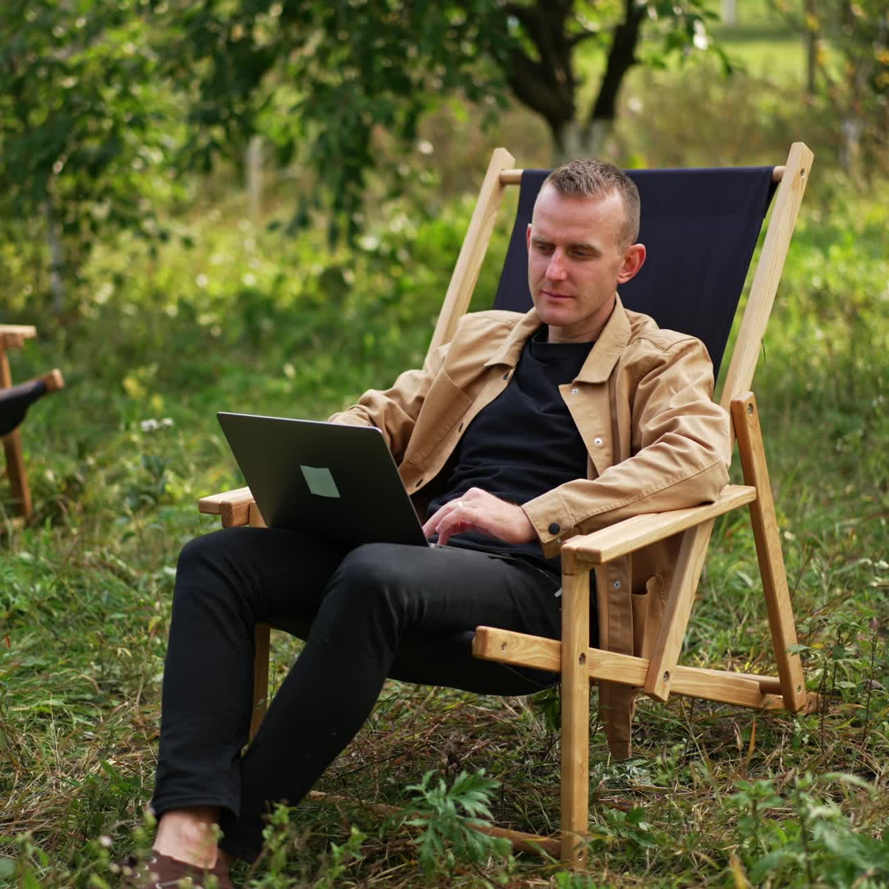 Relaxing with notebook. Handsome man with laptop in garden working