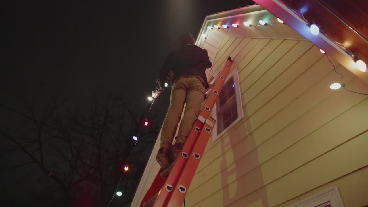 A man is on a ladder hanging christmas lights