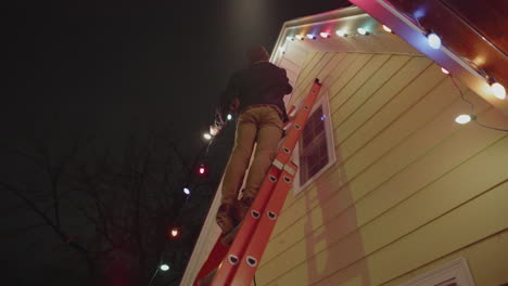 Un-Hombre-Está-En-Una-Escalera-Colgando-Luces-Navideñas