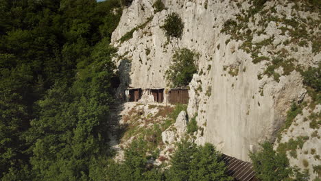 drone shot of a hiker walking under the clif of mountain sabotin past the house like structures