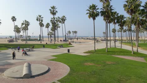 vista aérea cinematográfica de la gente de la playa de venecia en el parque chicos patinando