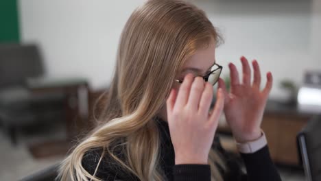 woman taking off her glasses in her office