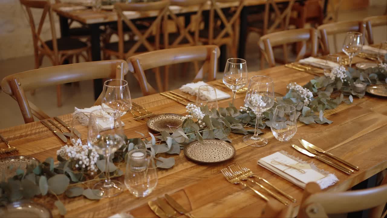 Elegant rustic wedding dinner table setting with glassware gold cutlery and floral decor