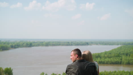 man embraces beloved woman enjoying view of tranquil river