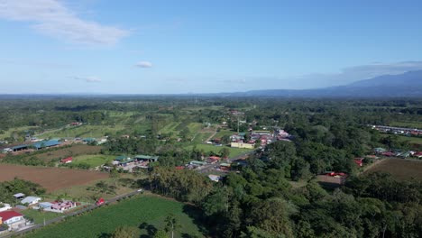 Drone-footage-of-approaching-flight-toward-a-small-central-American-town-with-vehicles-driving-out-of-the-frame-along-the-main-local-road