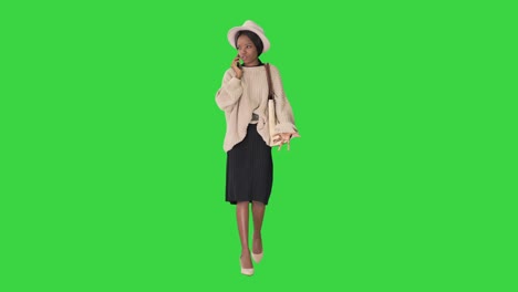 frustrated african american woman in knitted sweater and white hat talking on her phone on a green screen, chroma key