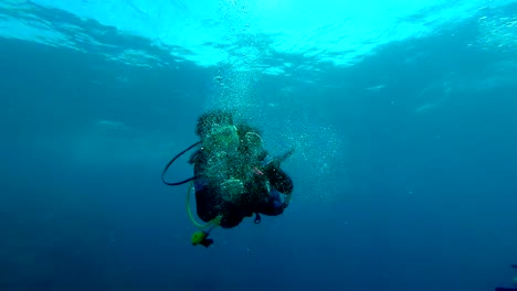 female scuba diver playing with scuba bubbles in the deep blue (slow motion)