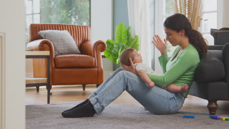 Liebevolle-Mutter-Spielt-Guck-A-Boo-Mit-Ihrem-Kleinen-Sohn,-Der-Zu-Hause-Auf-Dem-Boden-Sitzt