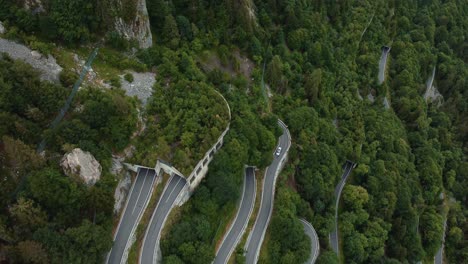 fliegen über der berühmten serpentinenstraße plöckenpass in italien durch die natürlichen österreichischen alpen im sommer mit grünen waldbäumen, tunneln und autos auf der straße